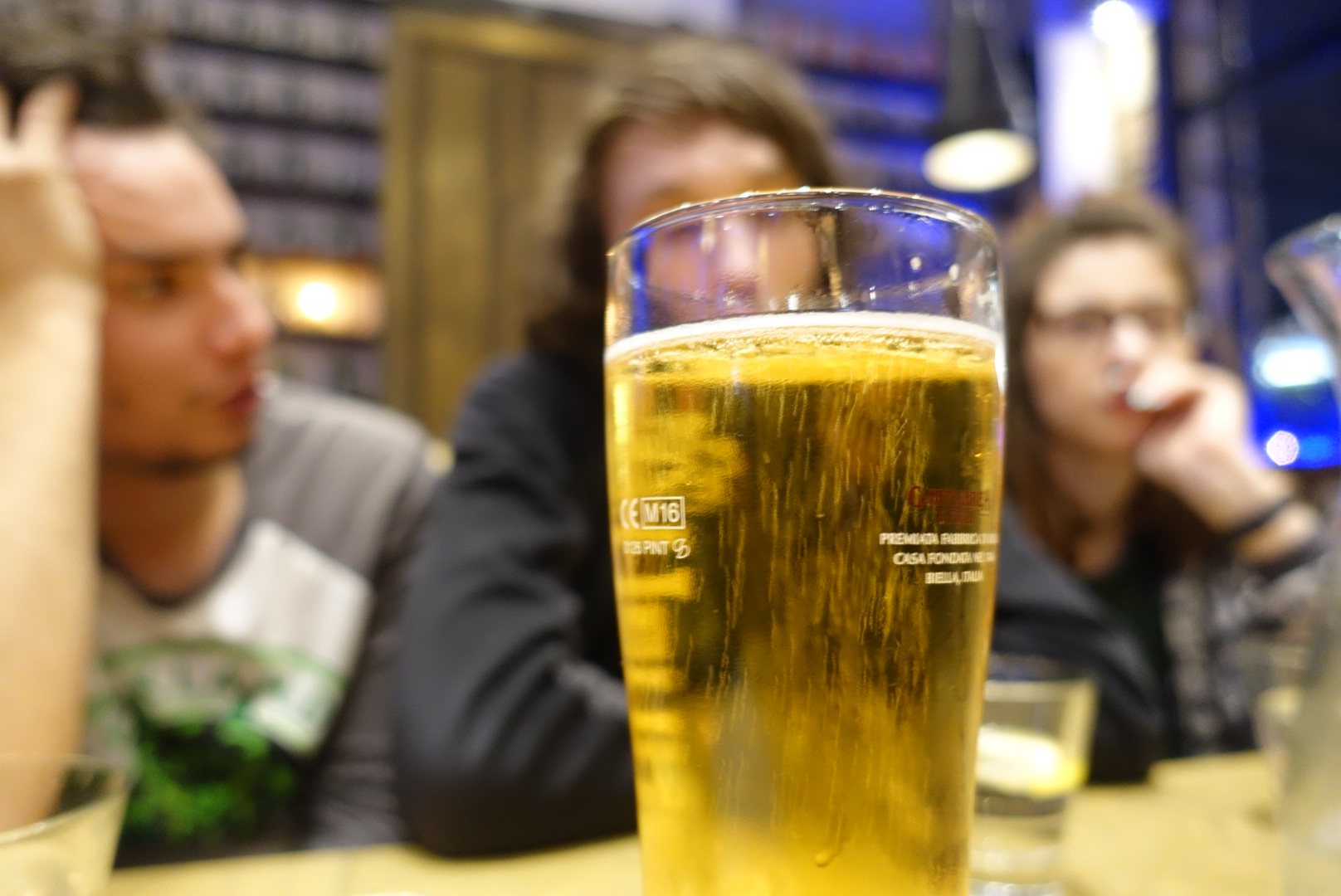 foreground: A glass of beeer. background: Liam, Lochie and Helena.